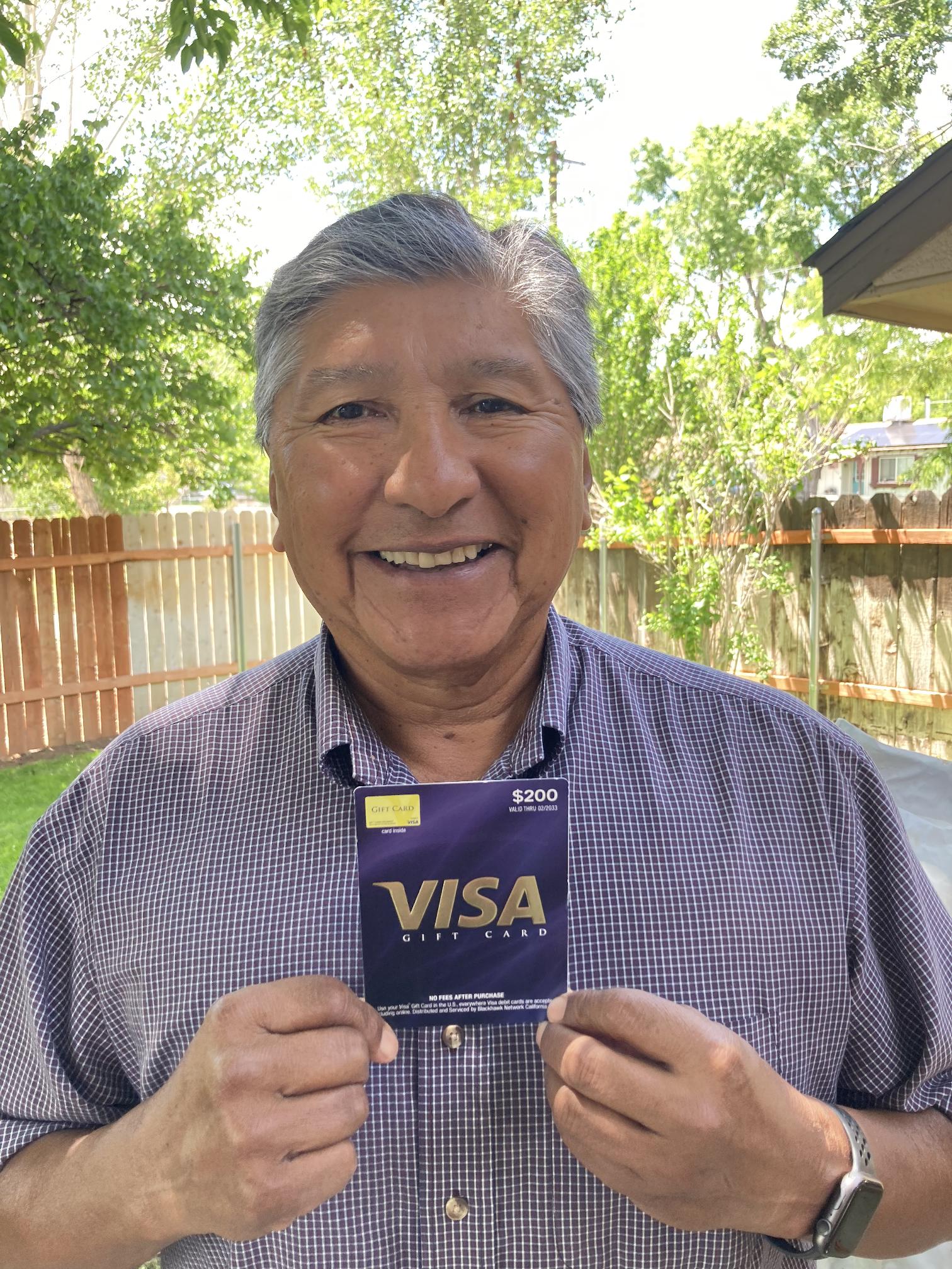 Man smiling and holding a Visa gift card