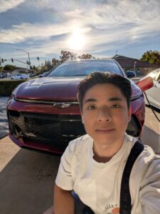Man posing next a charging electric car